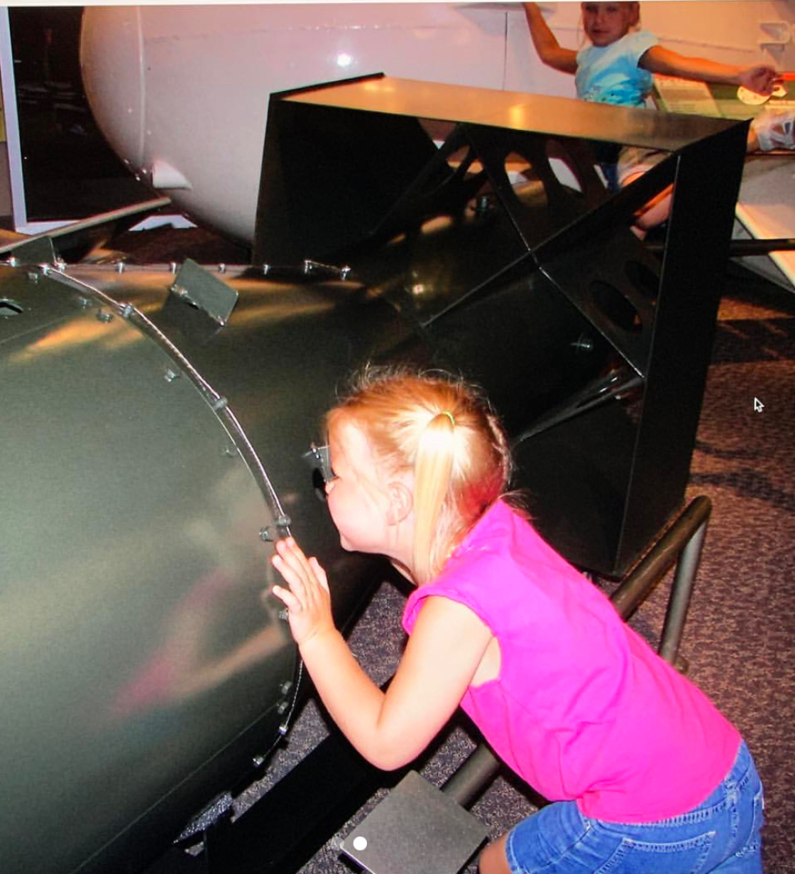 Lane Terry (back) poses next to the “Fat Man” atomic bomb while her sister (front) looks at the “Little Boy” bomb.