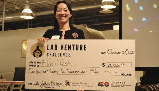 Flari Tech CEO Dr. Eva Yao stands with a check from the Lab Venture Challenge