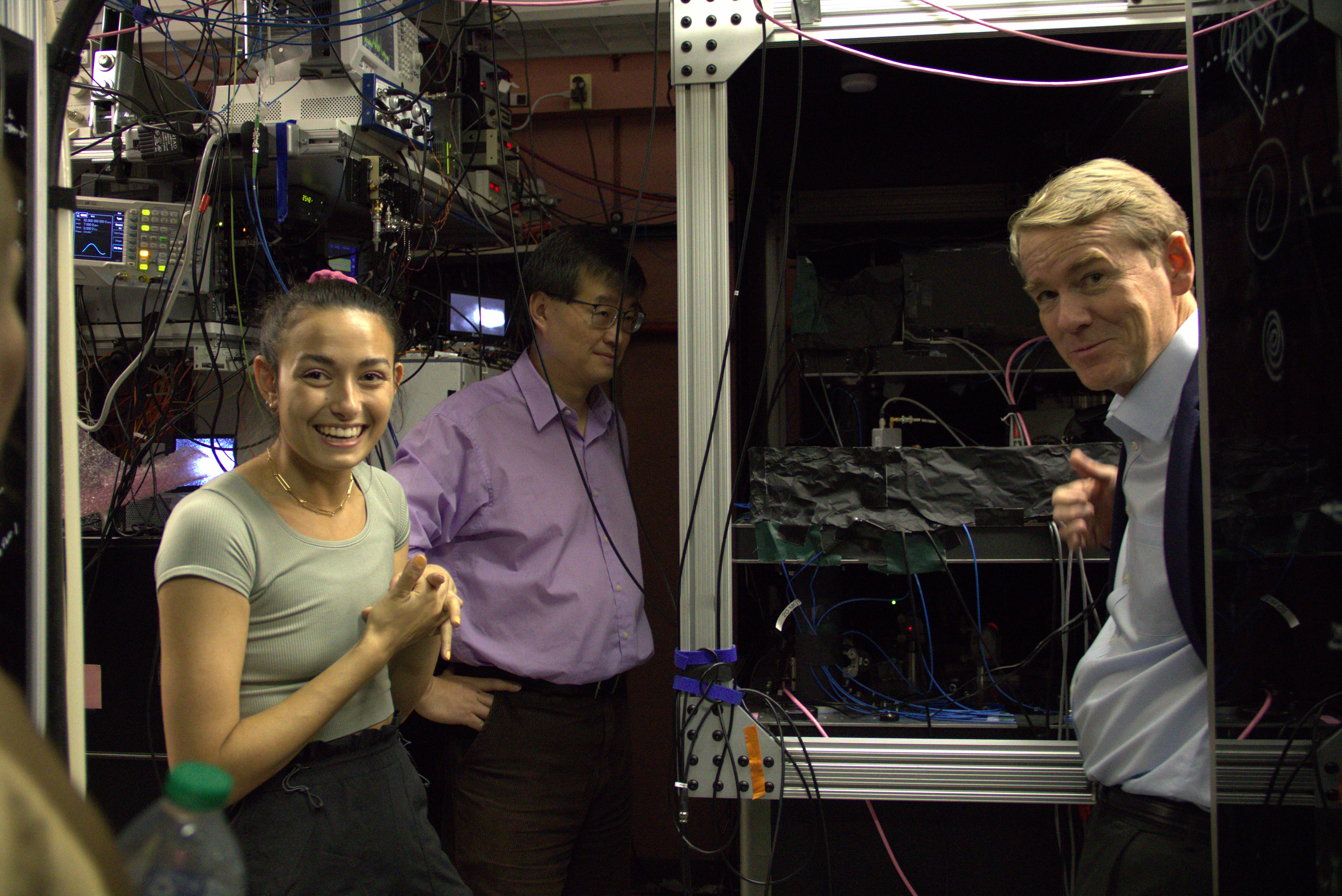 Senator Bennet (right) discusses atomic clock technology with graduate student Maya Miklos (left) and JILA and NIST Fellow Jun Ye (middle)