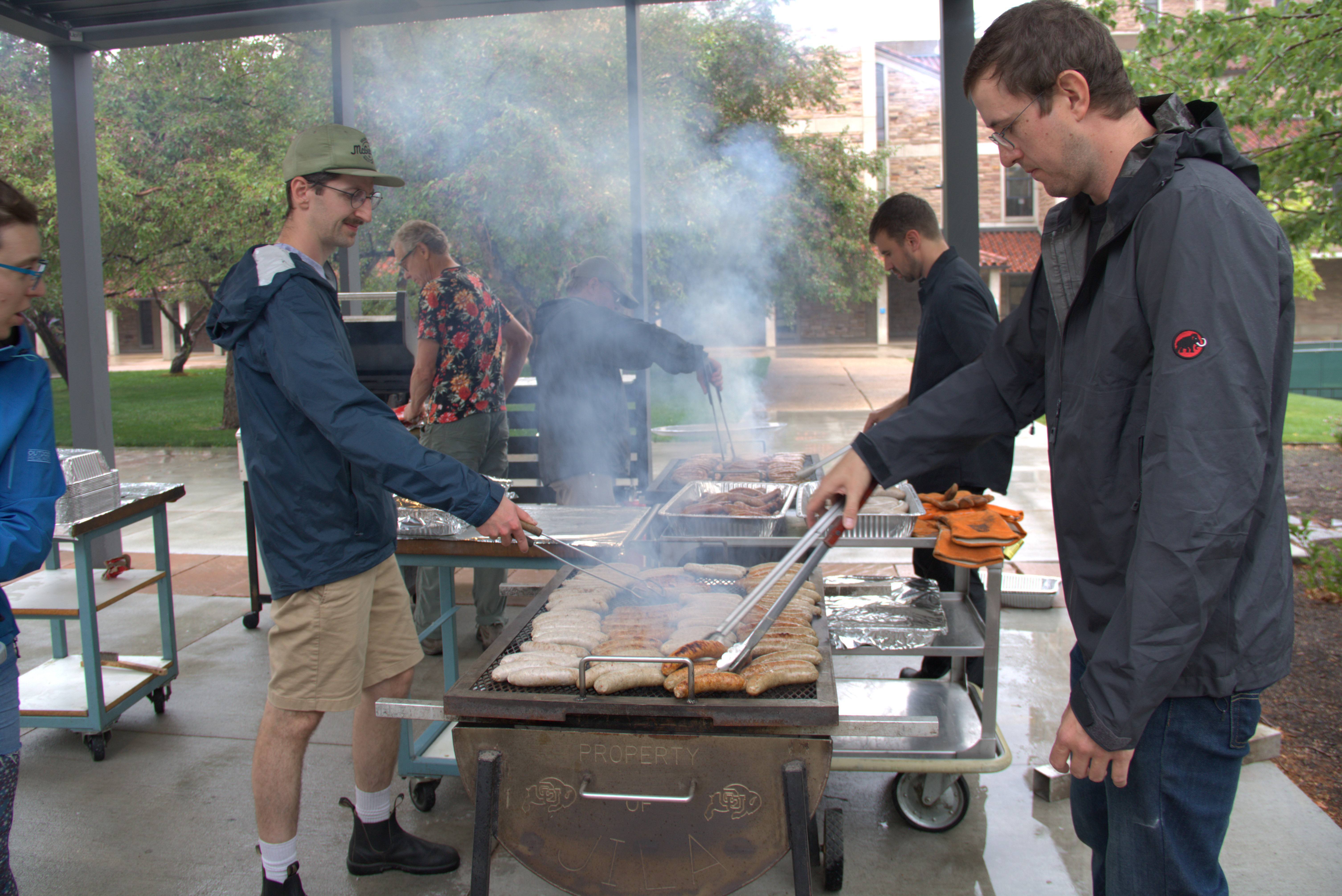 JILA instrument maker Kyle Thatcher (right) works with grill with fellow instrument maker Calvin Schwadron (left) during the brat cookout