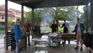 Members of the instrument shop smile while cooking over 500 brats for the annual JILA brat cookout